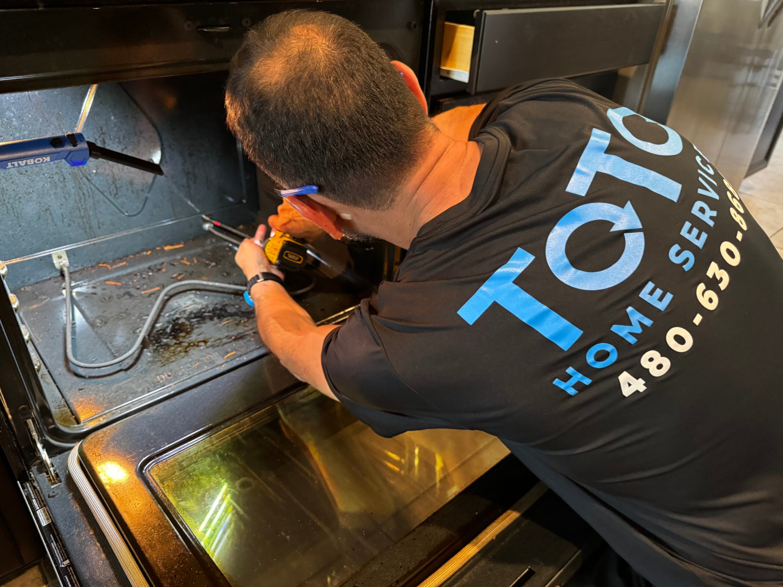 private-party-05 A technician from TOC Home Service using a power tool to repair the inside of an oven.